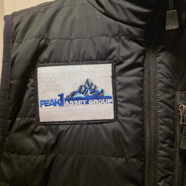 Completed black vest with Peak Asset Group embroidered logo patch